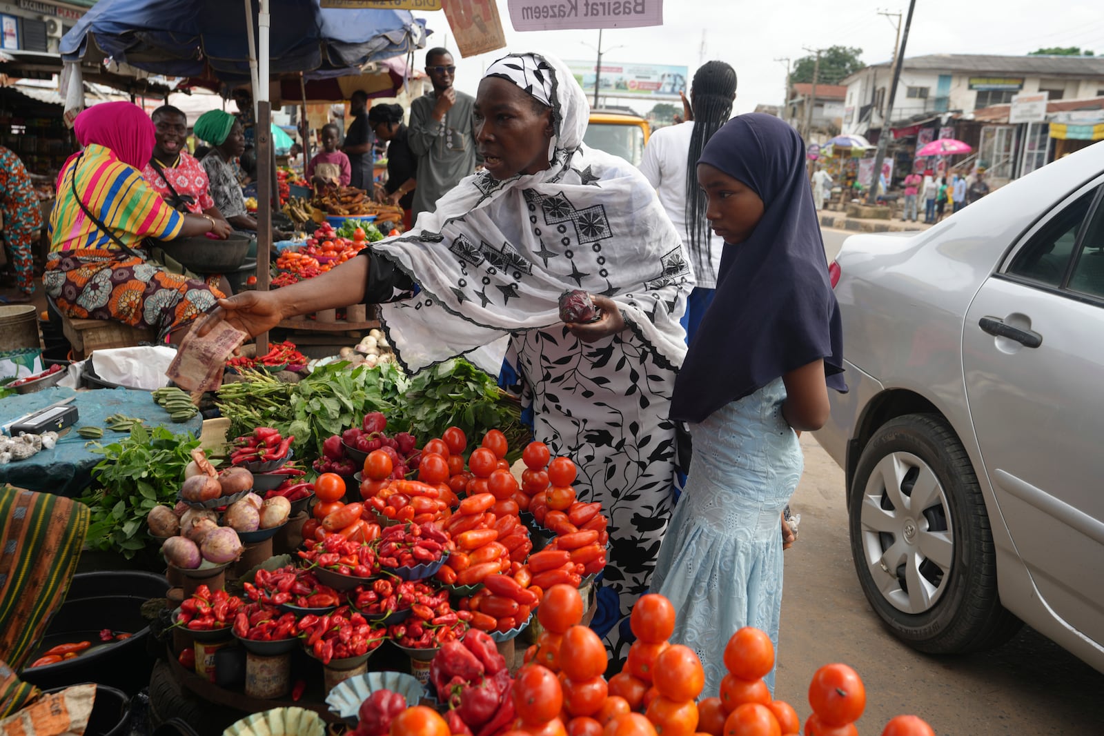 Idowu Bello, 56, buys onions to prepare a pot of soup at a market in Ibadan, Nigeria, Friday, Sept. 13, 2024. (AP Photo/Sunday Alamba)