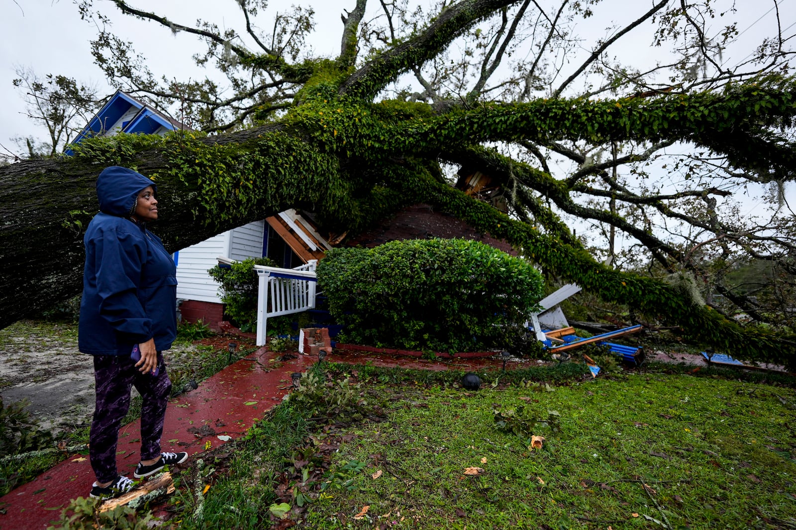 Ronda Bell looks on after an Oak tree landed on her 100-year-old home after Hurricane Helene moved through, Friday, Sept. 27, 2024, in Valdosta, Ga. (AP Photo/Mike Stewart)