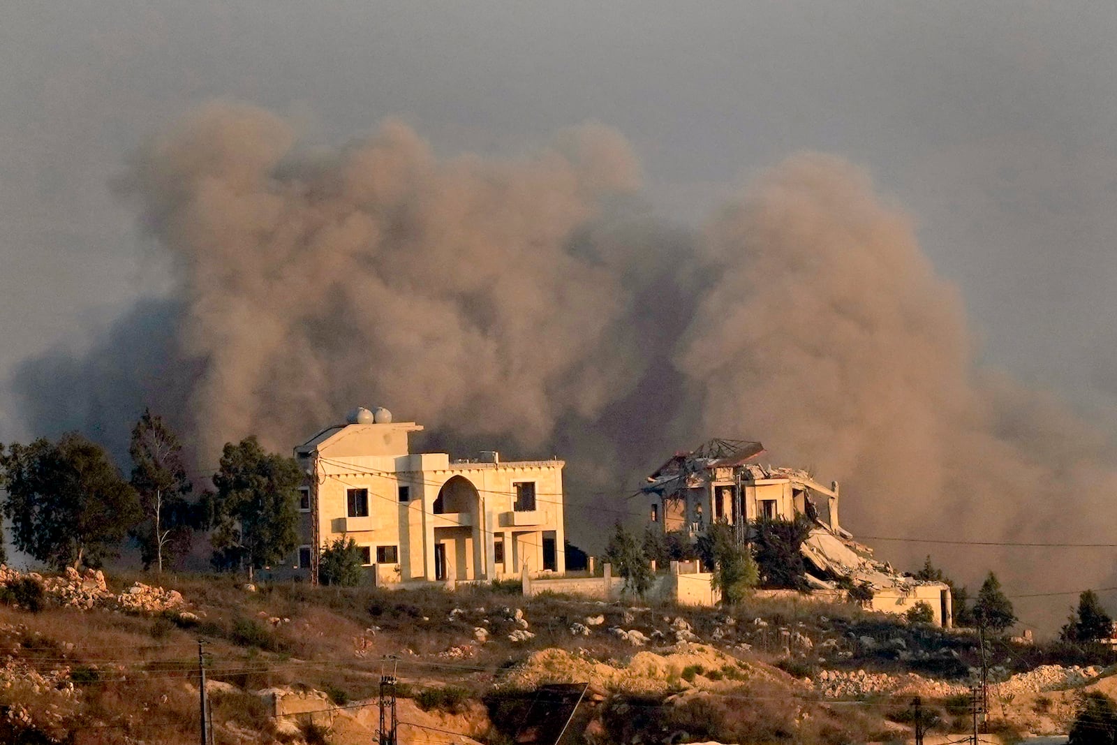 Smoke rises behind a destroyed house following an Israeli airstrike on Khiam village, as seen from Marjayoun town, south Lebanon, Tuesday, Sept. 24, 2024. (AP Photo/Hussein Malla)