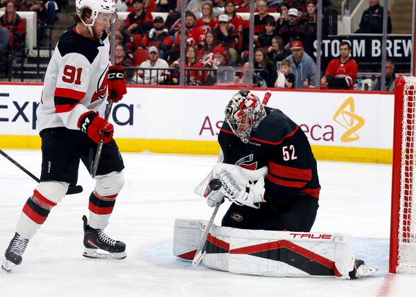 Carolina Hurricanes goaltender Pyotr Kochetkov (52) controls the puck in front of New Jersey Devils' Dawson Mercer (91) during the third period of Game 5 of an NHL hockey Stanley Cup first-round playoff series in Raleigh, N.C., Tuesday, April 29, 2025. (AP Photo/Karl DeBlaker)