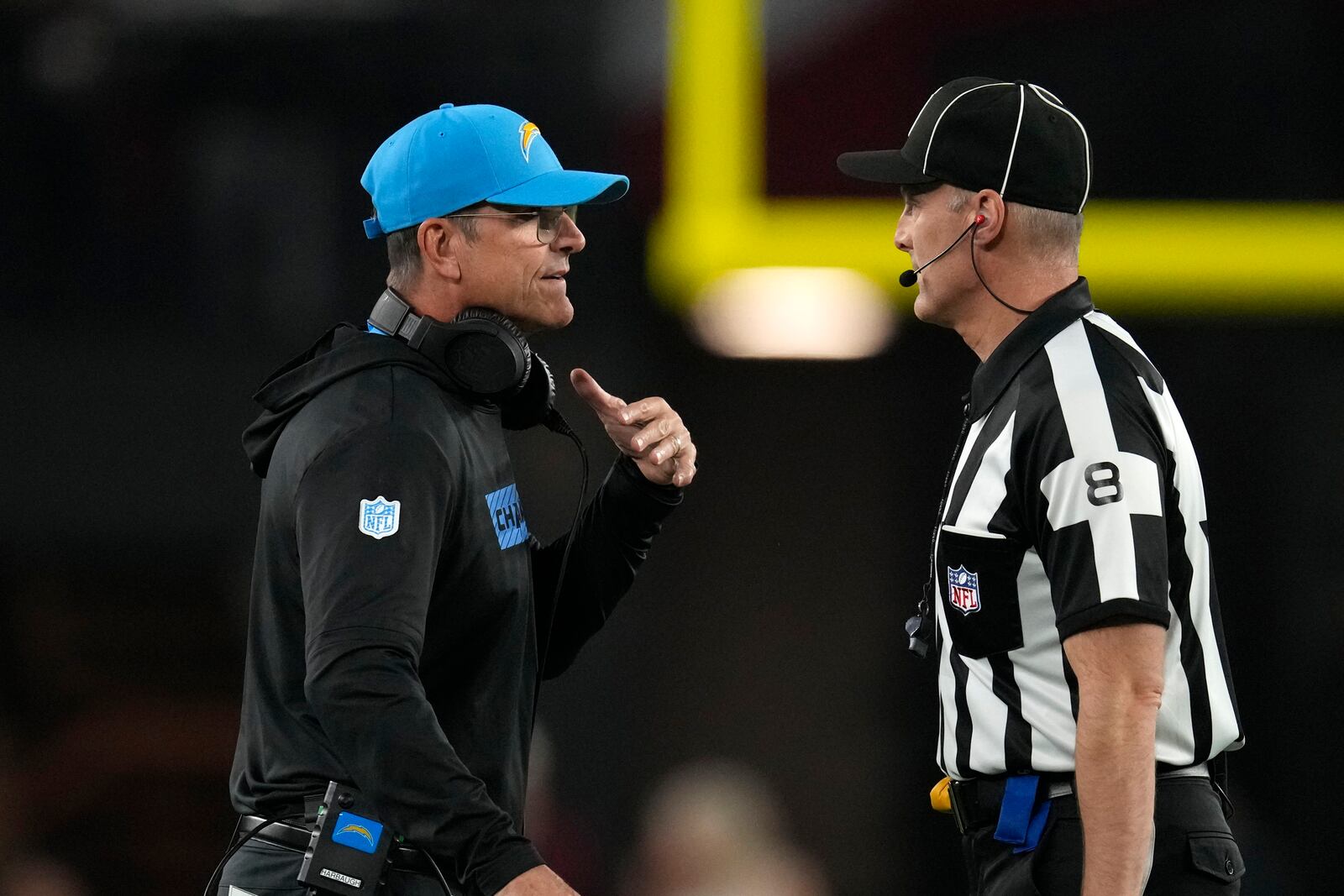 Los Angeles Chargers head coach Jim Harbaugh, left, talks with down judge Dana McKenzie, right, during the first half of an NFL football game against the Arizona Cardinals, Monday, Oct. 21, 2024, in Glendale Ariz. (AP Photo/Matt York)