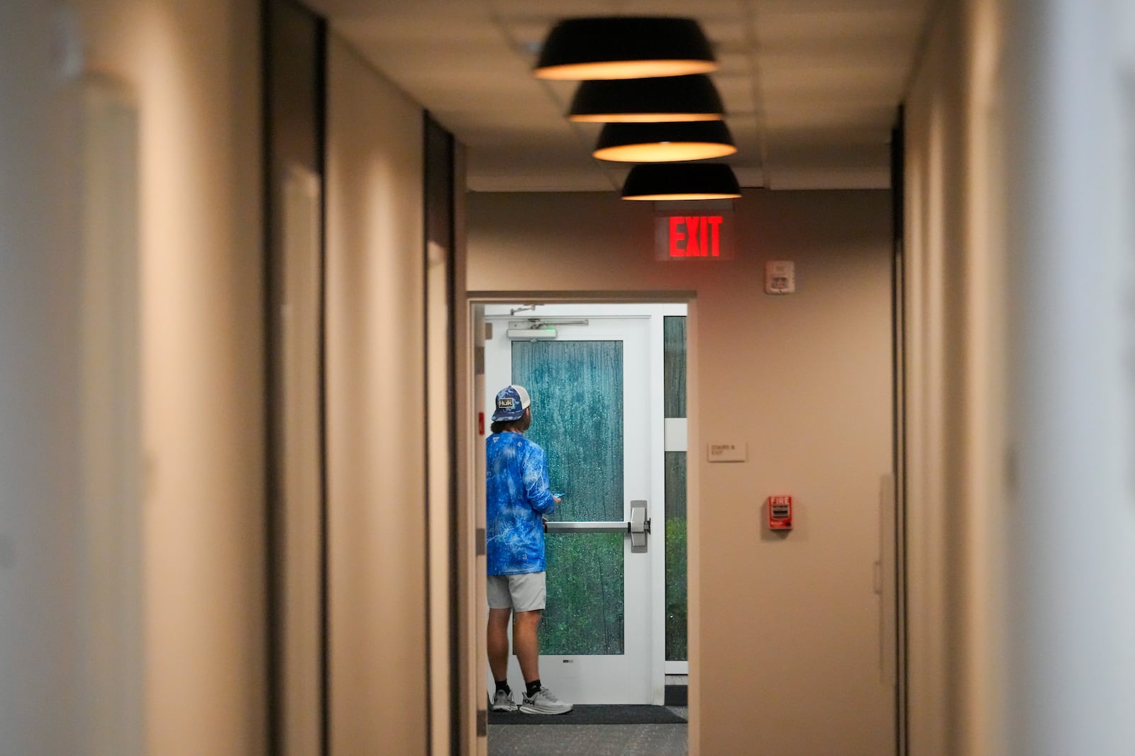 Davis Jones, an insurance adjuster from Biloxi, Miss., looks out the door of the hotel where he is riding out Hurricane Milton, Wednesday, Oct. 9, 2024, in Tampa, Fla. (AP Photo/Julio Cortez)