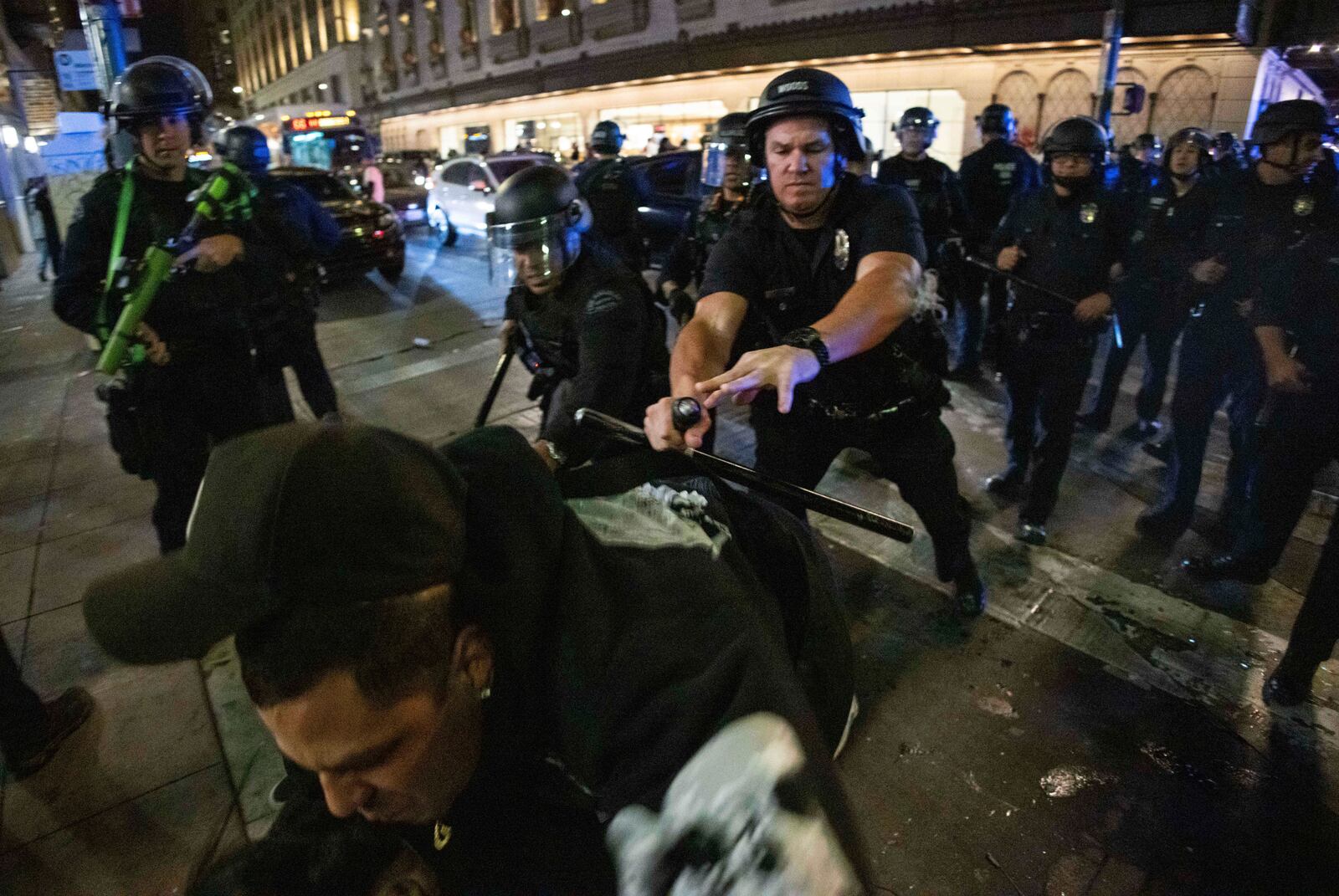 Police officers attempt to detain a man as people gather on the streets after the Los Angeles Dodgers won against the New York Yankees in the baseball World Series Wednesday, Oct. 30, 2024, in Los Angeles. (AP Photo/Ethan Swope)