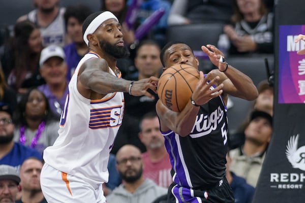 Phoenix Suns forward Royce O'Neale, left, knocks the ball from Sacramento Kings guard De'Aaron Fox (5) during the second half of an NBA basketball game in Sacramento, Calif., Wednesday, Nov. 13, 2024. (AP Photo/Randall Benton)