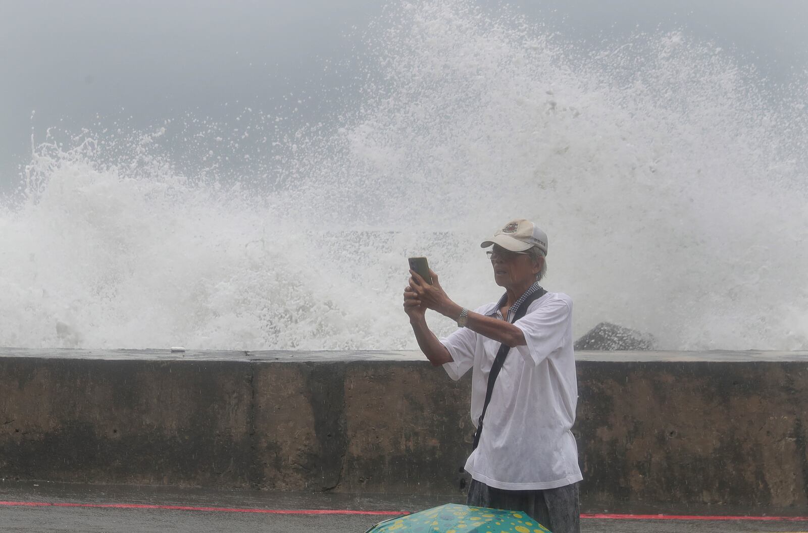 A man takes a selfie with waves hitting the shore of Kaohsiung, southern Taiwan, Wednesday, Oct. 2, 2024, as Typhoon Krathon is expected to hit the area. (AP Photo/Chiang Ying-ying)