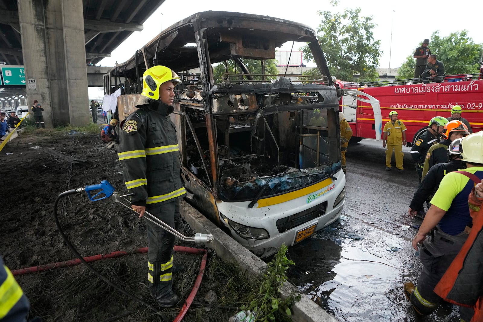 Rescuers work at the site of a bus that caught fire, carrying young students with their teachers, in suburban Bangkok, Tuesday, Oct. 1, 2024. (AP Photo/Sakchai Lalit)