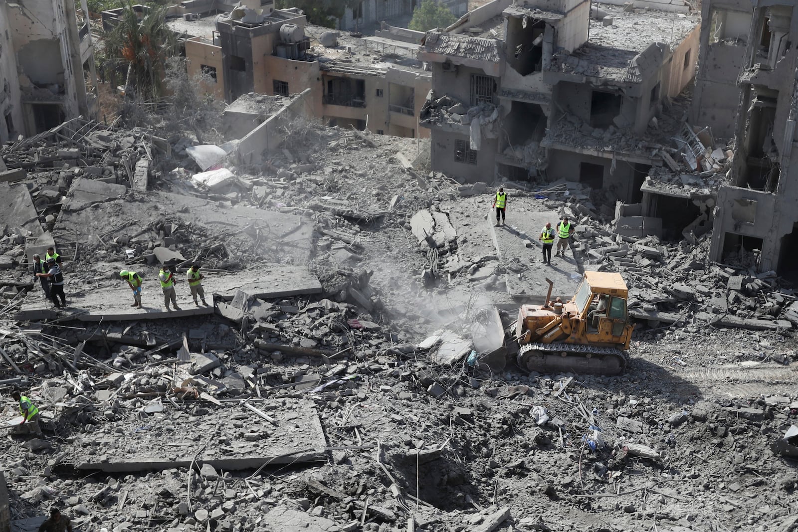 Rescue workers use a bulldozer to remove rubble of destroyed buildings at the site that was hit by Israeli airstrikes in Qana village, south Lebanon, Wednesday, Oct. 16, 2024. (AP Photo/Mohammed Zaatari)