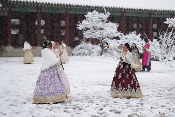 Mary Joy Morcisa from Philippines, right, gestures in snow at the Gyeongbok Palace, one of South Korea's well-known landmarks, in Seoul, South Korea, Wednesday, Nov. 27, 2024. (AP Photo/Lee Jin-man)