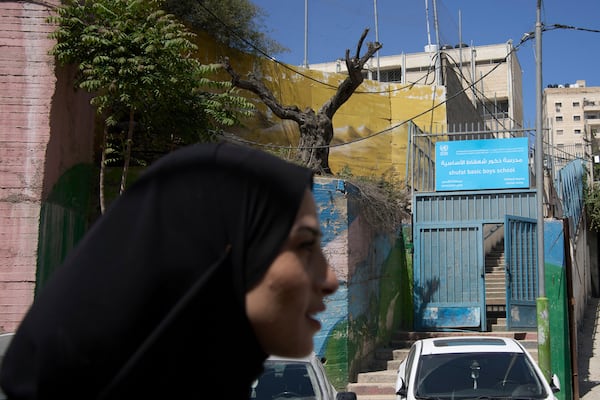A woman passes the front entrance to the UNRWA Boys' School run by the U.N. agency for Palestinian refugees in the Shuafat Refugee Camp in east Jerusalem, Tuesday, April 29, 2025. (AP Photo/Maya Alleruzzo)