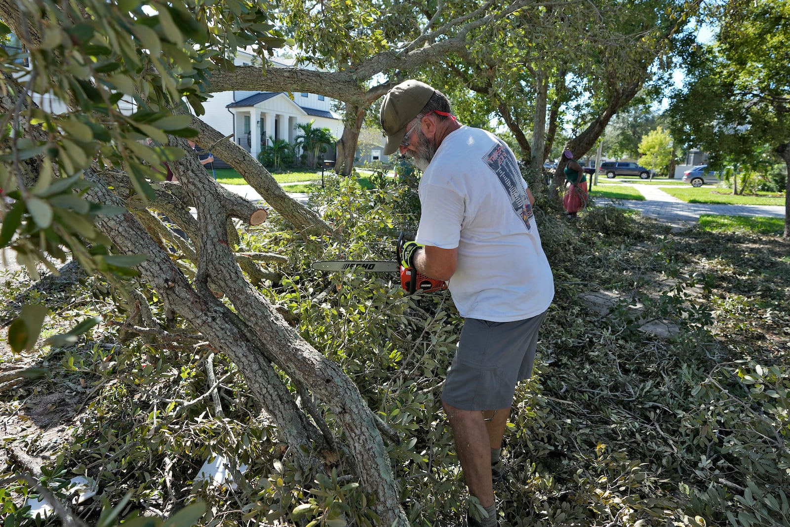 Brian Malone cuts down a tree, which fell during Hurricane Milton, outside a neighbor's home Sunday, Oct. 13, 2024, in Tampa, Fla. (AP Photo/Chris O'Meara)