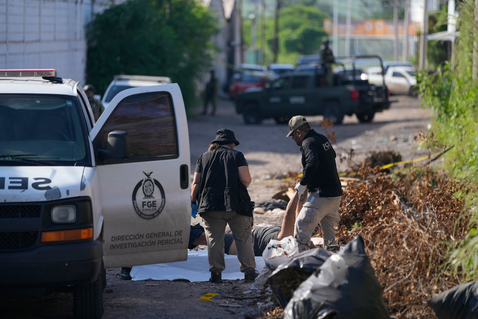 Forensic investigators remove a body from the street in La Costerita, Culiacan, Sinaloa state, Mexico, Thursday, Sept. 19, 2024. (AP Photo/Eduardo Verdugo)