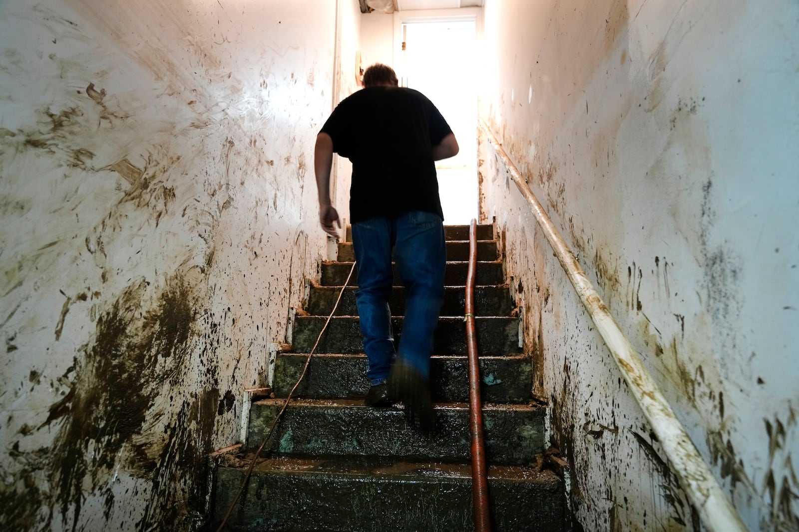 Contractor Joshua Taylor walks up stairs covered in mud leading to the basement of a funeral home that was flooded in the aftermath of Hurricane Helene while working to clean up the building Saturday, Oct. 5, 2024, in Newport, Tenn. (AP Photo/Jeff Roberson)