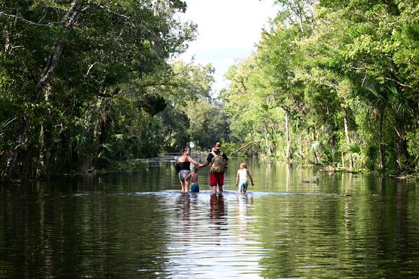 FILE - Dustin Holmes, second from right, holds hands with his girlfriend, Hailey Morgan, while returning to their flooded home with her children Aria Skye Hall, 7, right, and Kyle Ross, 4, in the aftermath of Hurricane Helene, Sept. 27, 2024, in Crystal River, Fla. (AP Photo/Phelan M. Ebenhack, File)