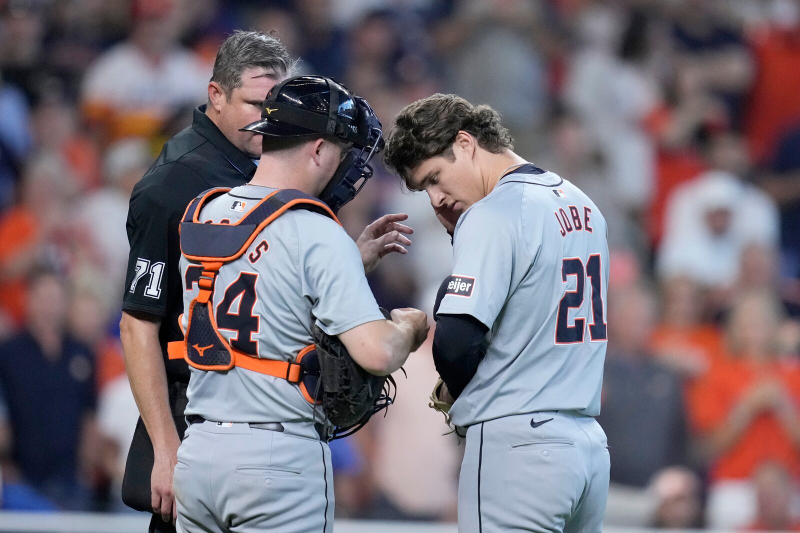 Detroit Tigers catcher Jake Rogers (34) and relief pitcher Jackson Jobe (21) work on Jobe's communications device as home plate umpire Jordan Baker (71) looks on in the seventh inning of Game 2 of an AL Wild Card Series baseball game Wednesday, Oct. 2, 2024, in Houston. (AP Photo/Kevin M. Cox)