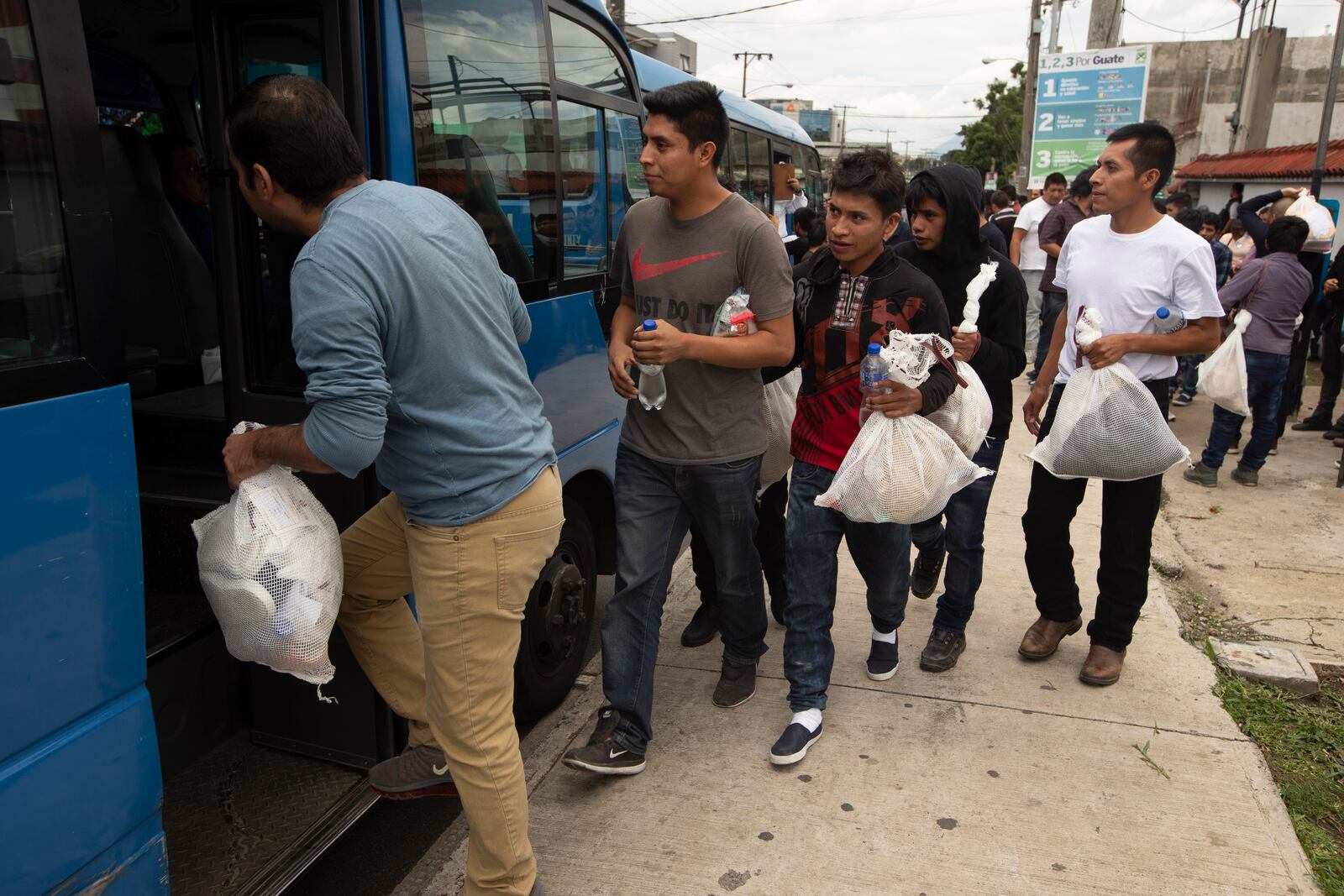 FILE - Guatemalan men who were deported from the United States, board a bus after arriving at the Air Force Base in Guatemala City, on July 16, 2019. (AP Photo/Moises Castillo, File)