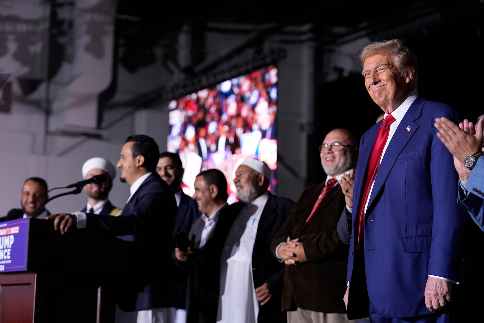 Republican presidential nominee former President Donald Trump, right, looks on as local Muslim leaders speak during a campaign rally at the Suburban Collection Showplace, Saturday, Oct. 26, 2024, in Novi, Mich. (AP Photo/Alex Brandon)