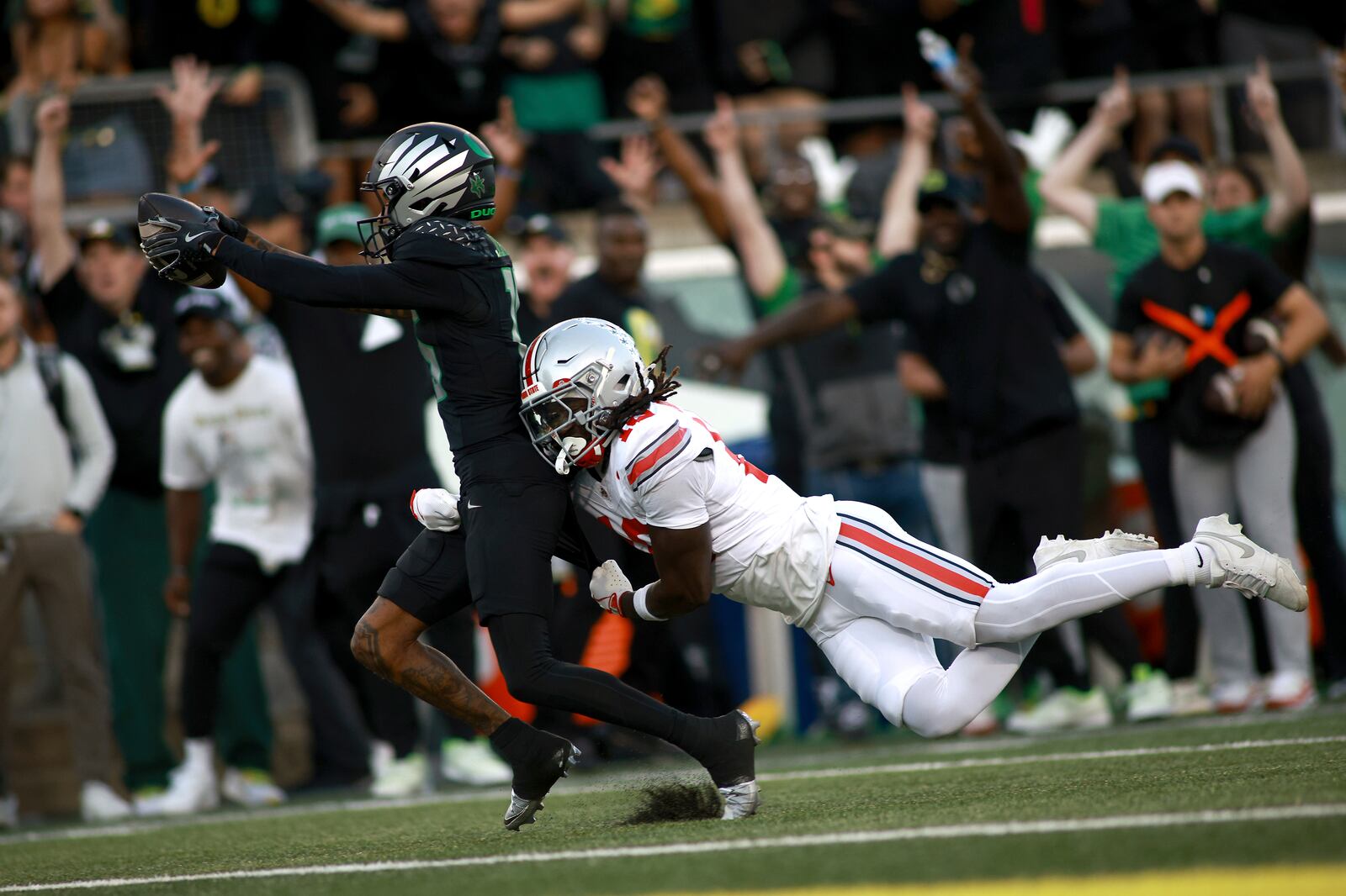 Oregon wide receiver Tez Johnson, left, escapes a tackle by Ohio State cornerback Denzel Burke, right, for a touchdown during an NCAA college football game, Saturday, Oct. 12, 2024, in Eugene, Ore. (AP Photo/Lydia Ely)