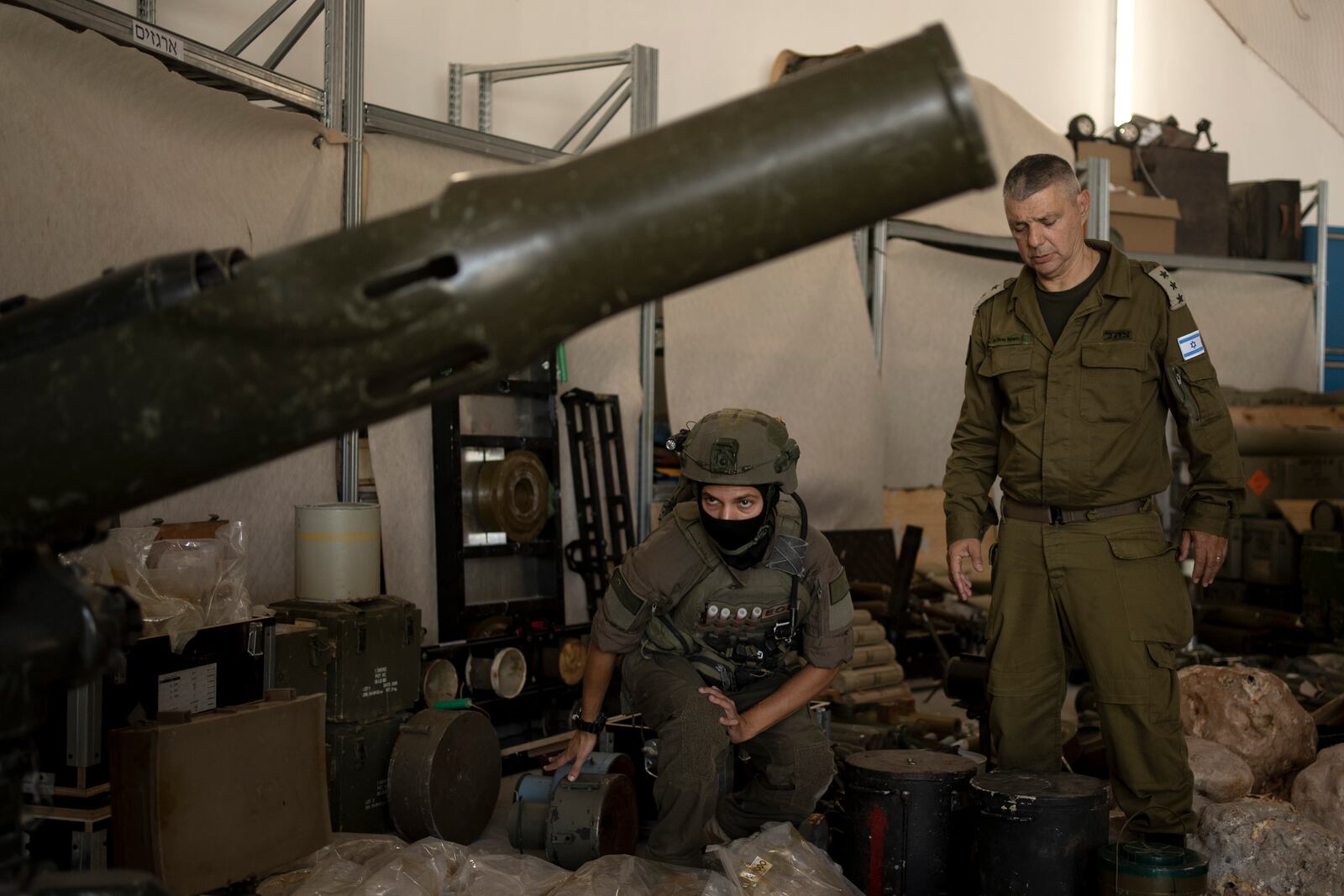 An Israeli soldier from an EOD (explosive ordnance disposal) unit, left, and an officer from the Israel Defense Forces Spokesperson's Unit walk through weapons used by Hezbollah seized during combat operations in Lebanon displayed during a government-organized media tour on a base in southern Israel, Wednesday, Oct. 9, 2024. (AP Photo/Maya Alleruzzo)