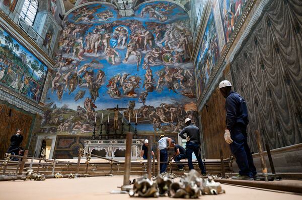In this image taken on Monday, April 28, 2025, and made available Saturday, May 3, 2025, by Vatican Media, workers prepare the Sistine Chapel at the Vatican, where the upcoming conclave will start May 7, backdropped by Michelangelo Buonarroti's fresco 'The Last Judgement'. (Vatican Media via AP)