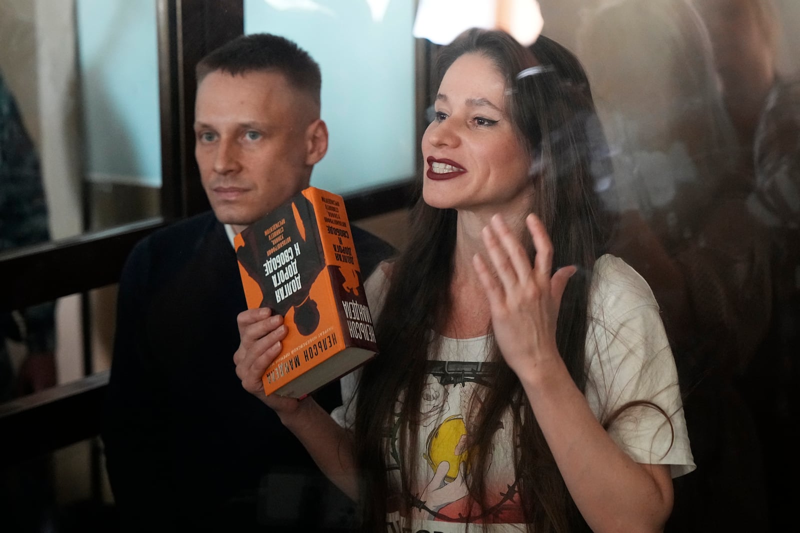 Russian journalists Konstantin Gabov, left, and Antonina Favorskaya, accused of working for a group founded by the late Russian opposition politician Alexei Navalny, stand in a defendant's cage of the Nagatinsky District Court in Moscow, Russia, on Wednesday, Oct. 2, 2024. (AP Photo)