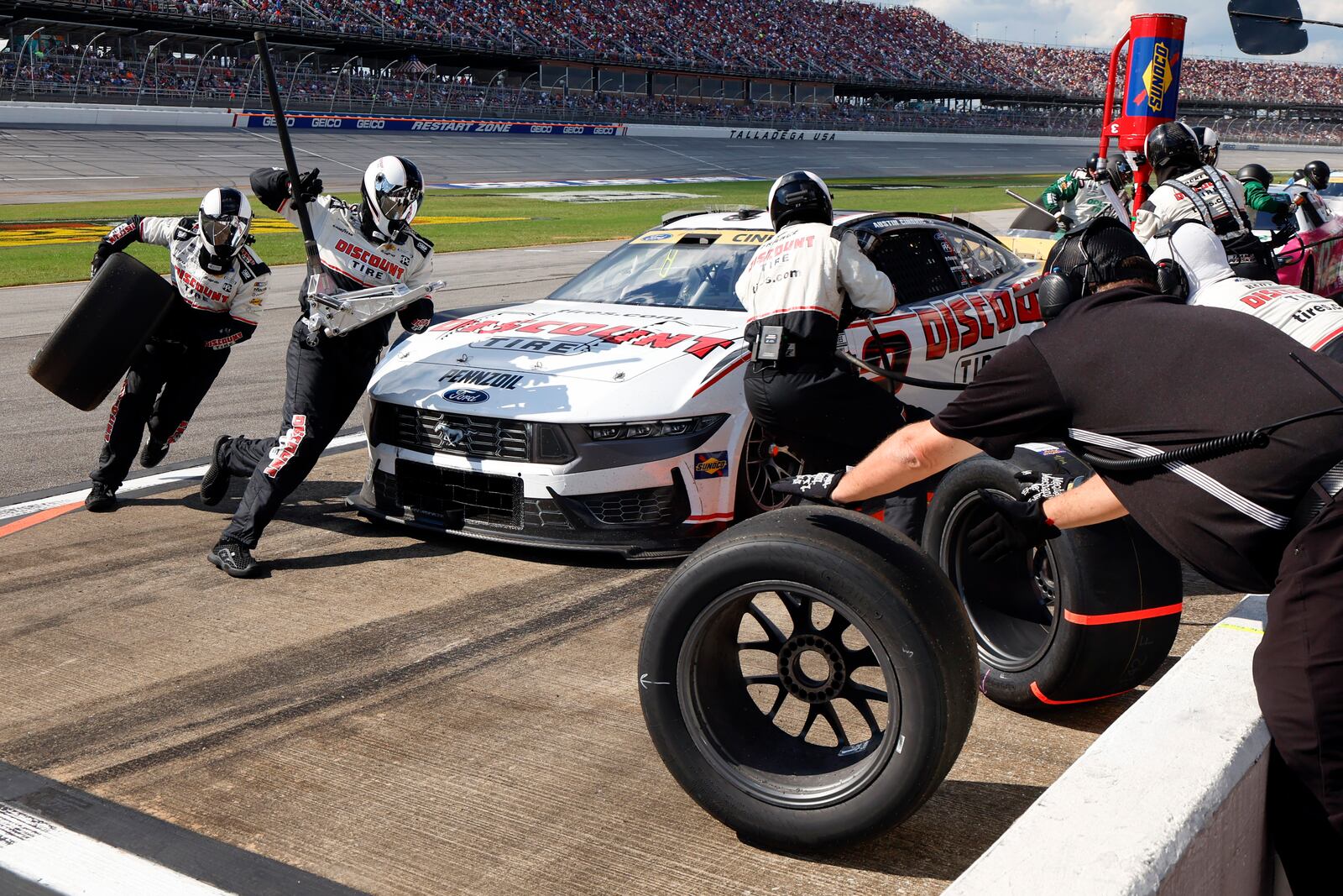 Crew members for driver Austin Cindric change tires during a NASCAR Cup Series auto race at Talladega Superspeedway, Sunday, Oct. 6, 2024, in Talladega, Ala. (AP Photo/ Butch Dill)