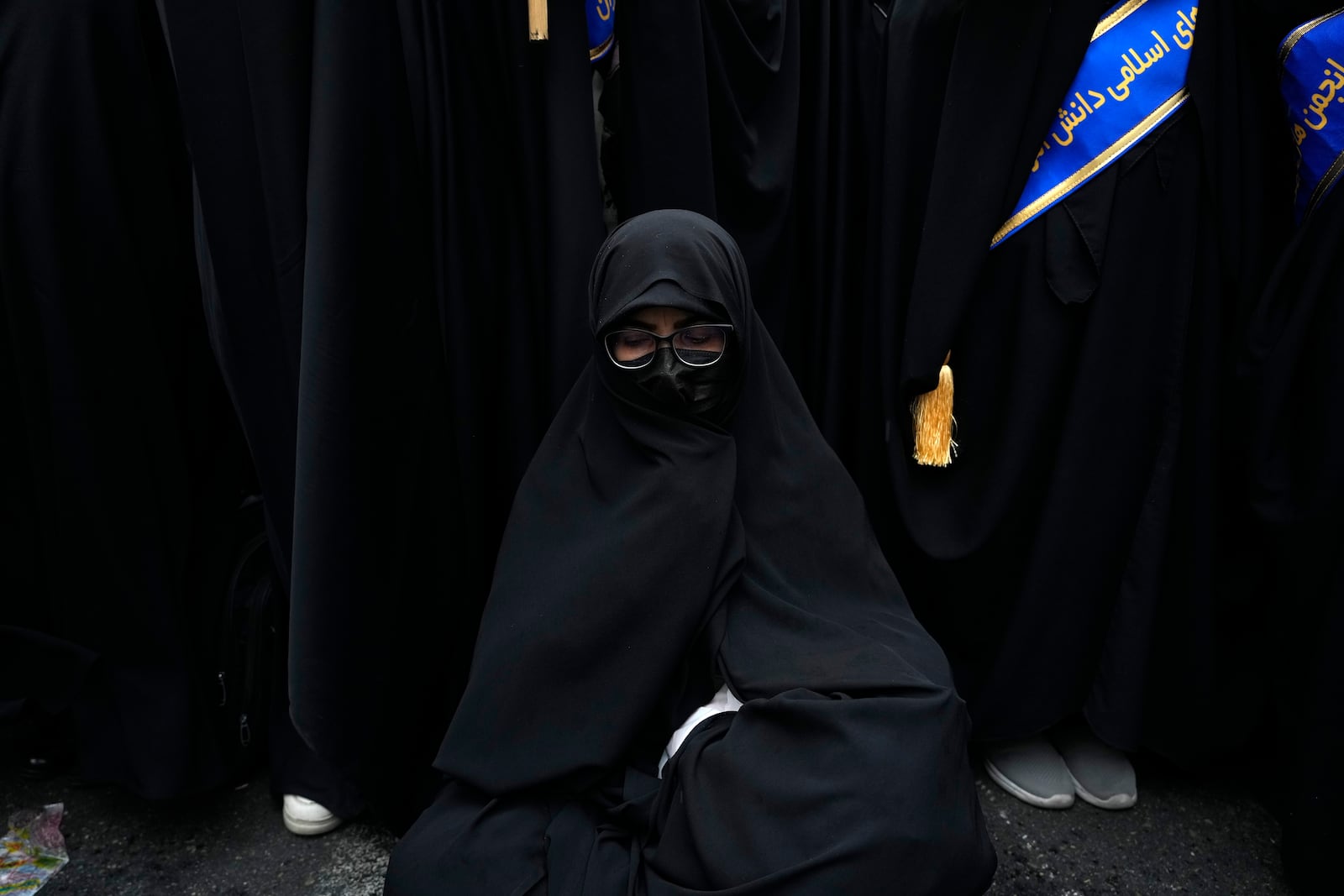 An Iranian woman sits as she attends an annual rally in front of the former U.S. Embassy in Tehran, Iran, Sunday, Nov. 3, 2024, marking the 45th anniversary of Iranian students' takeover of the embassy, starting a hostage crisis. (AP Photo/Vahid Salemi)