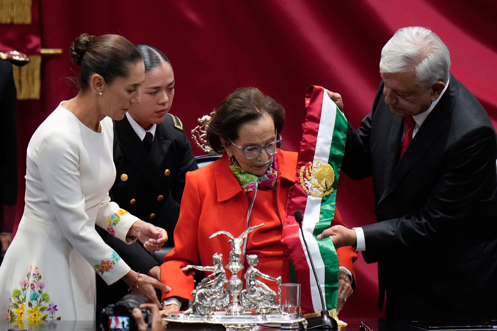 Outgoing President Andres Manuel Lopez Obrador hands over the presidential sash to Ifigenia Martinez, president of the Chamber of Deputies, during the swearing-in ceremony of Claudia Sheinbaum, left, at Congress in Mexico City, Tuesday, Oct. 1, 2024. (AP Photo/Eduardo Verdugo)