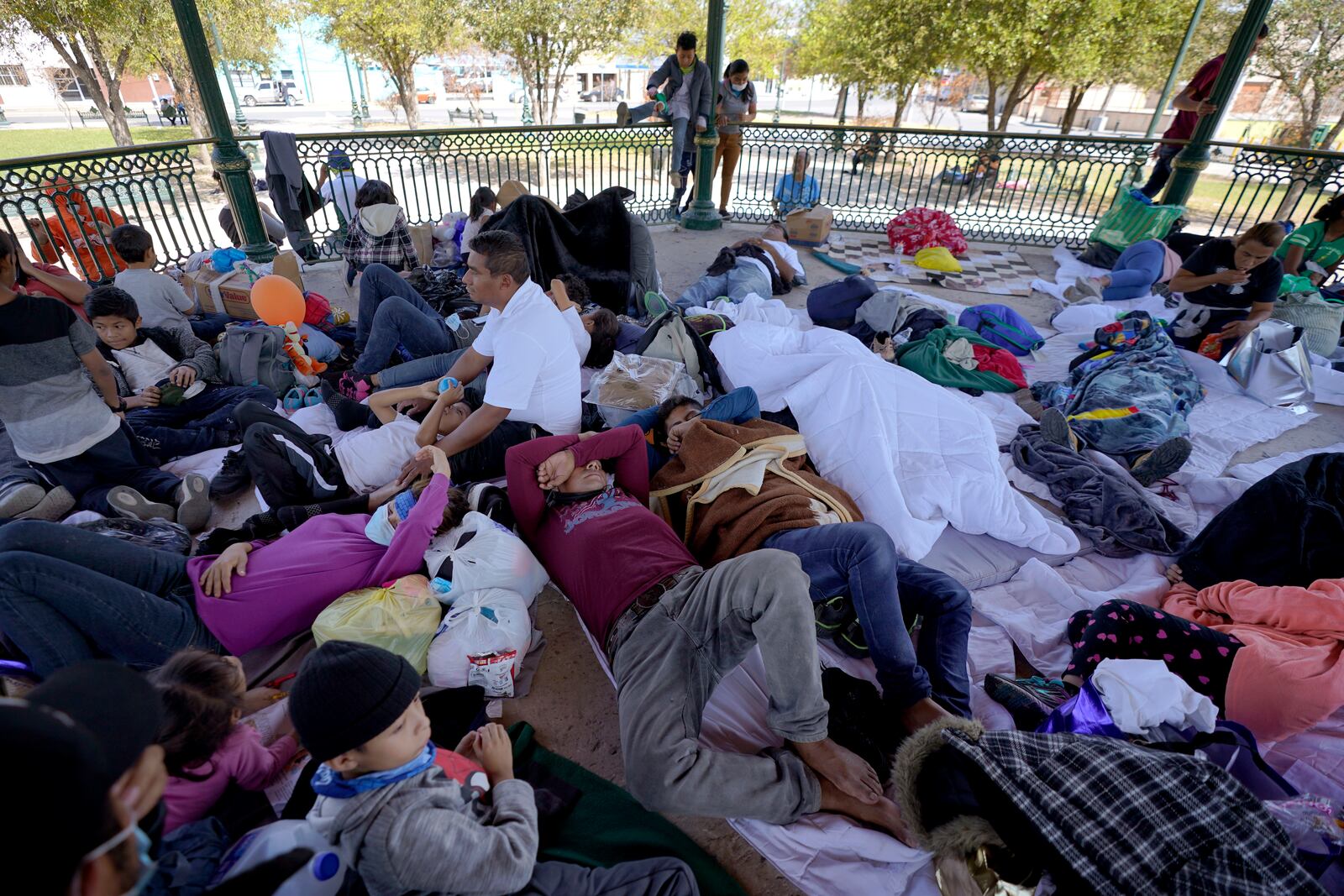 FILE - A group of migrants rest on a gazebo at a park after the deportees from the U.S. were pushed by Mexican authorities off an area they had been staying after their expulsion, on March 20, 2021, in Reynosa, Mexico. (AP Photo/Julio Cortez, File)