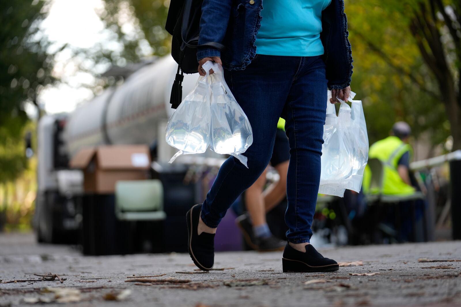 A person carries bags of fresh water after filling up from a tanker at a distribution site in the aftermath of Hurricane Helene Wednesday, Oct. 2, 2024, in Asheville, N.C. (AP Photo/Jeff Roberson)