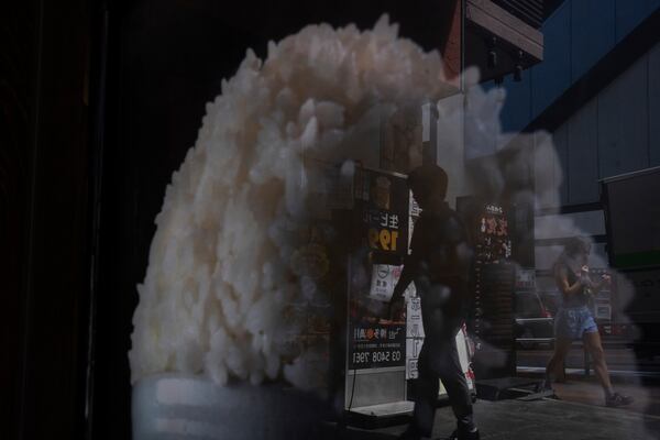 Pedestrians are reflected in the window of a restaurant advertising for rice in Tokyo, Thursday, May 22, 2025. (AP Photo/Louise Delmotte)
