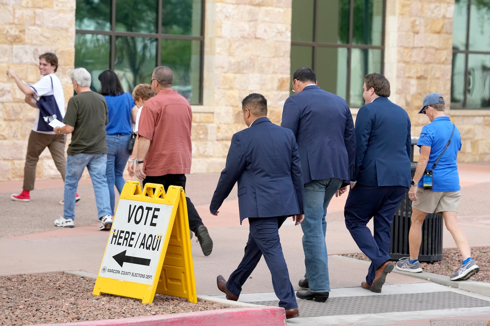 Arizona Secretary of State Adrian Fontes, third from right, and Greg Whitten, second from right, Democratic candidate for Arizona's 8th Congressional District, arrive with a group of voters on the first day of early in-person voting at Surprise City Hall, Wednesday, Oct. 9, 2024, in Surprise, Ariz. (AP Photo/Ross D. Franklin)