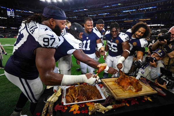 Dallas Cowboy players grab some turkey following an NFL football game against the New York Giants in Arlington, Texas, Thursday, Nov. 28, 2024. (AP Photo/Richard Roriguez)