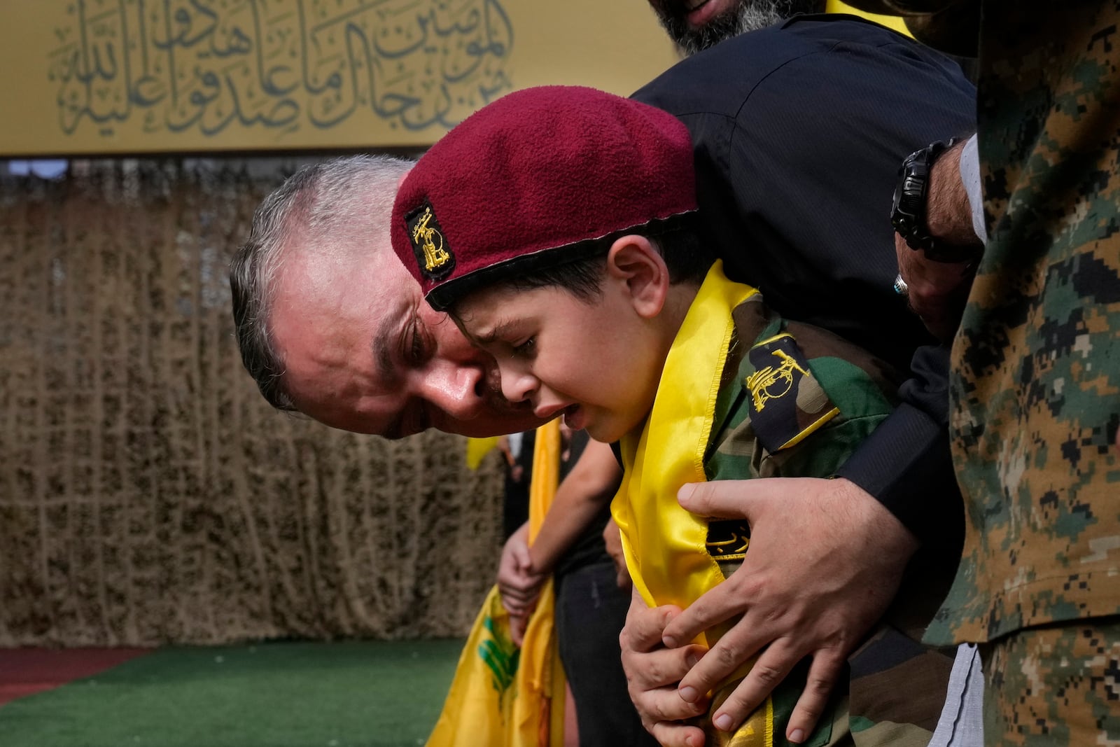 A man comforts a boy crying during the funeral procession of Hezbollah members in the southern suburbs of Beirut, Thursday, Sept. 19, 2024. (AP Photo/Hussein Malla)