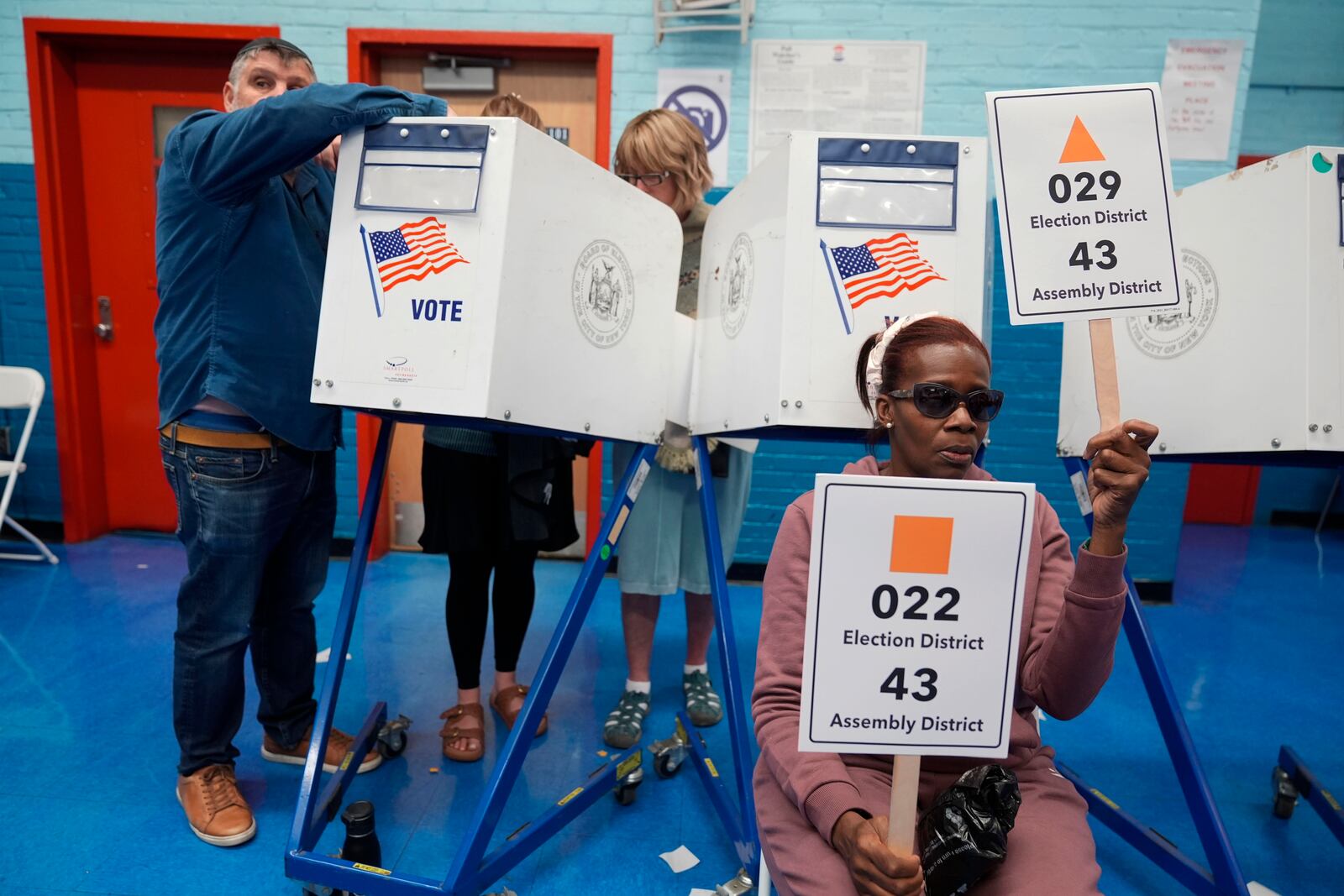 Poll worker Marion Jordan-Mcfarlane helps guide voters to get their ballots at a busy polling site in the Brooklyn borough of New York, Tuesday, Nov. 5, 2024. (AP Photo/Seth Wenig)