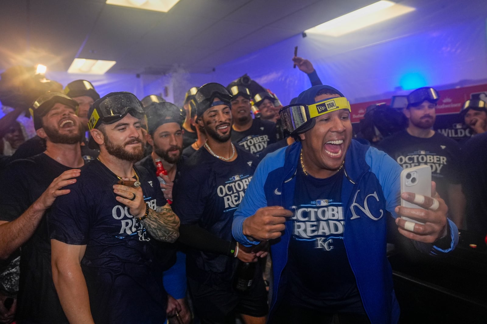 Kansas City Royals catcher Salvador Perez, right, holds a cell phone as he and teammates celebrate after defeating the Baltimore Orioles 2-1 in Game 2 of an AL Wild Card Series baseball game, Wednesday, Oct. 2, 2024 in Baltimore. (AP Photo/Stephanie Scarbrough)