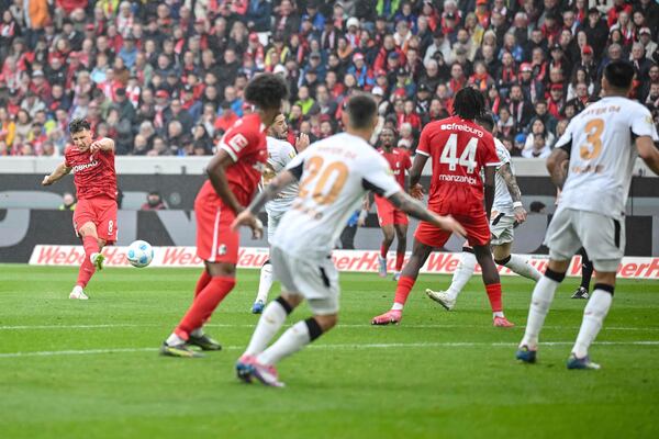 Freiburg's Maximilian Eggestein, left, takes a shot on goal, during the German Bundesliga soccer match between, SC Freiburg and Bayer Leverkusen, at Europa-Park Stadium, in Freiburg im Breisgau, Germany, Sunday, May 4, 2025. (Harry Langer/dpa via AP)