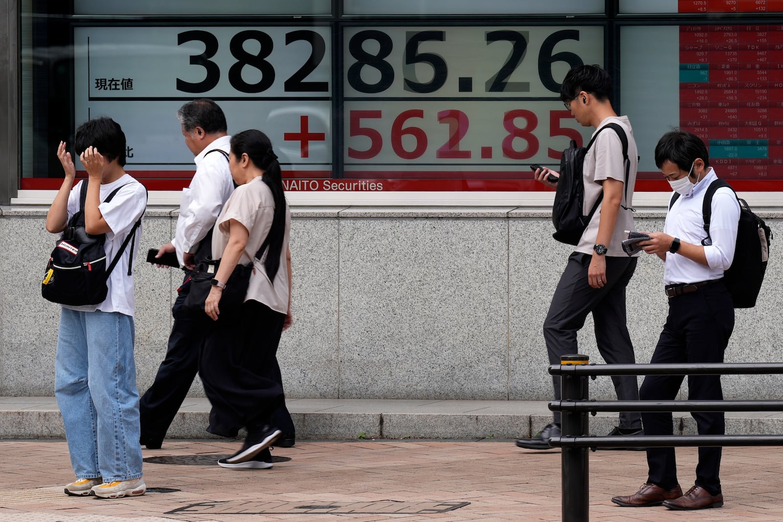 People walk in front of an electronic stock board showing Japan's Nikkei index at a securities firm Tuesday, Sept. 24, 2024, in Tokyo. (AP Photo/Eugene Hoshiko)