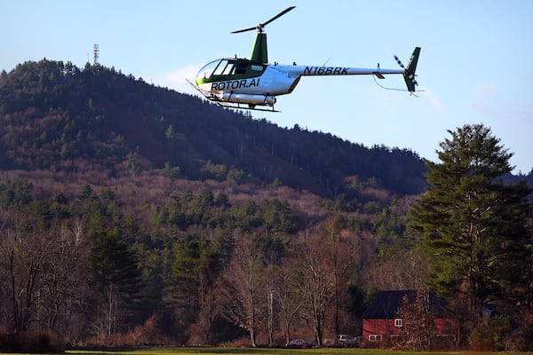 A Rotor Technologies unmanned semi-autonomous helicopter flies near Pat's Peak ski area, rear, during a test flight over Intervale Airport, Monday, Nov. 11, 2024, in Henniker, N.H. (AP Photo/Charles Krupa)