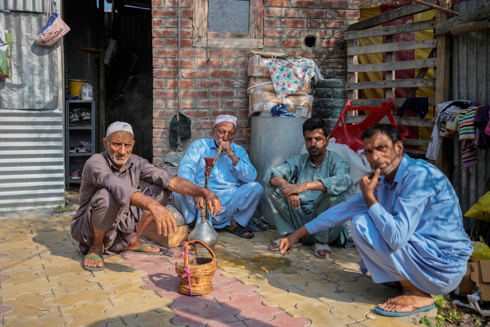 FILE- An elderly man smokes a hookah pipe as he sits with other men outside a polling station during the second phase of the assembly election in the interior of Dal Lake in Srinagar, Indian controlled Kashmir, Sept. 25, 2024.(AP Photo/Mukhtar Khan, File)