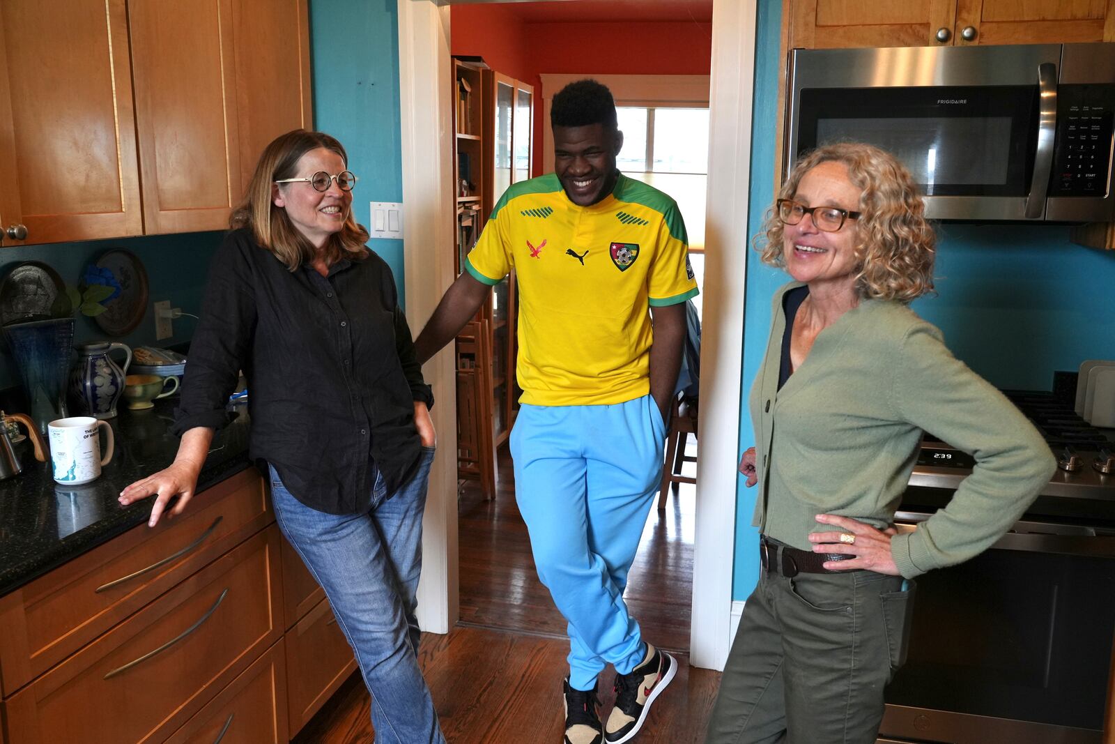 Cabrel Ngougou, center, a refugee from Cameroon, talks with his sponsors Lori Ostlund, left, and Anne Raeff in their home in San Francisco Tuesday, Sept. 17, 2024. (AP Photo/Terry Chea)