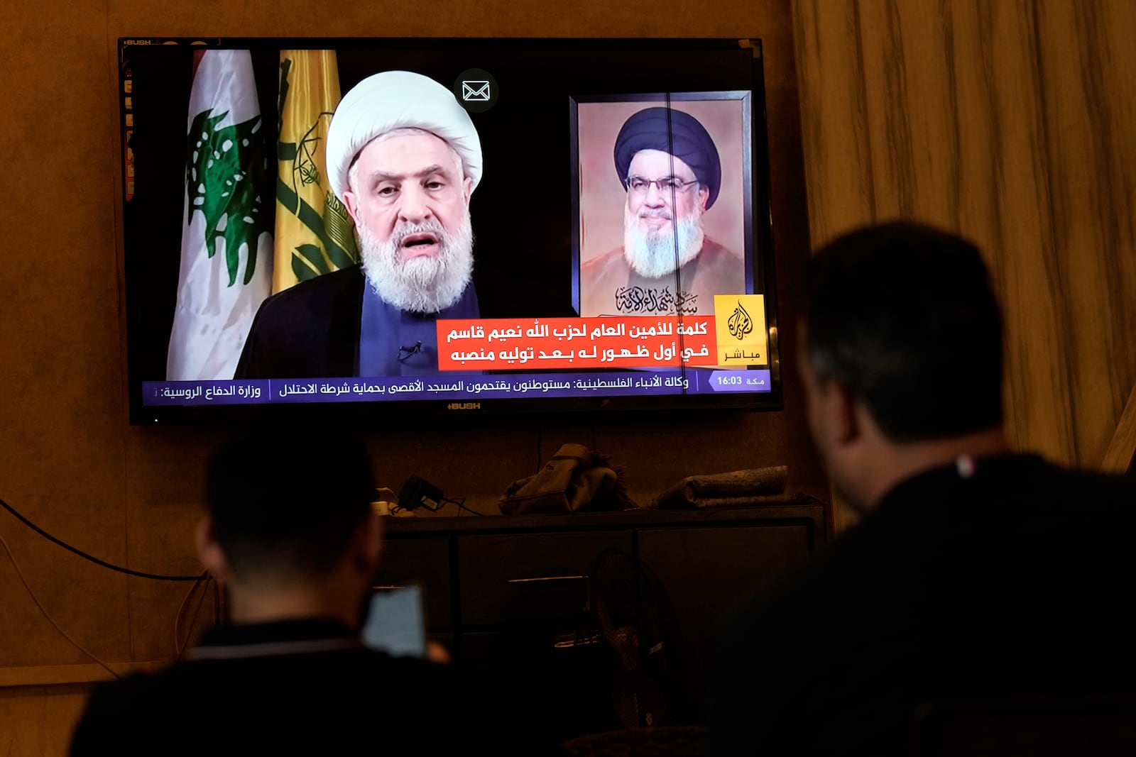 People watch Hezbollah's newly named leader Naim Kassem delivering a televised speech, in the southern port city of Sidon, Lebanon, Wednesday, Oct. 30, 2024. (AP Photo/Bilal Hussein)