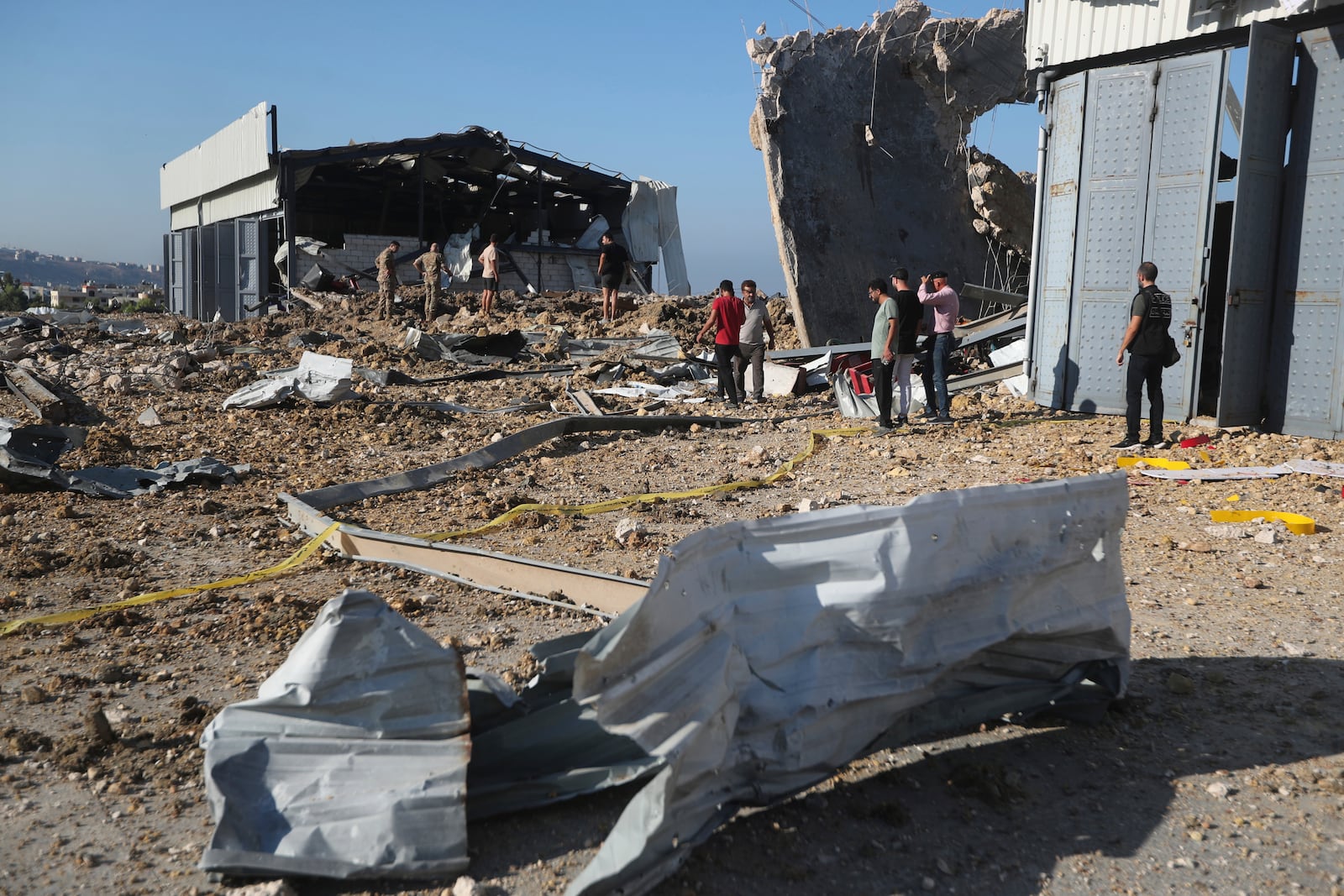 People gather near the site of an Israeli airstrike that hit a hangar in the southern town of Jiyeh, Lebanon, Wednesday, Sept. 25, 2024. (AP Photo/Mohammed Zaatari)