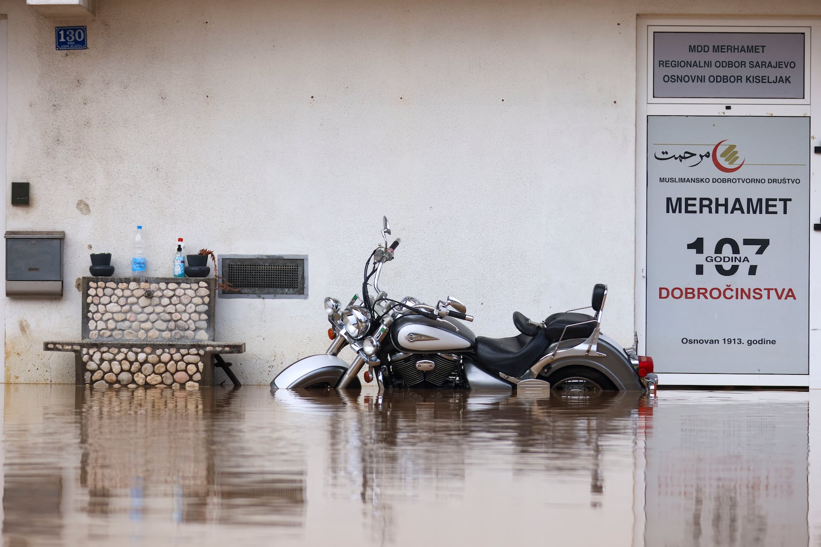 A motorcycle is partially submerged in flood waters outside an apartment building in the village of Kiseljak, northern Bosnia, Friday, Oct. 4, 2024. (AP Photo/Armin Durgut)