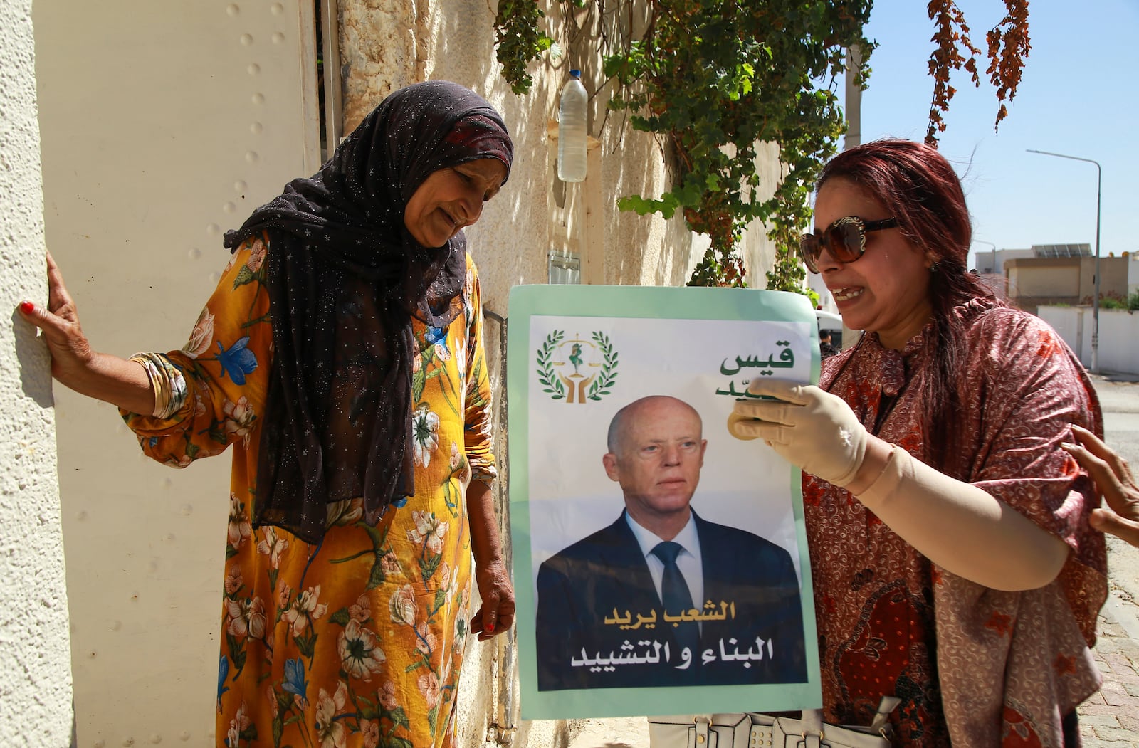 A supporter of Tunisian President and candidate for re-election Kais Saied meets with residents of a neighbourhood during a campaign tour, in Ariana, Tunisia, Thursday, Sept. 26, 2024. (AP Photo/Anis Mili)