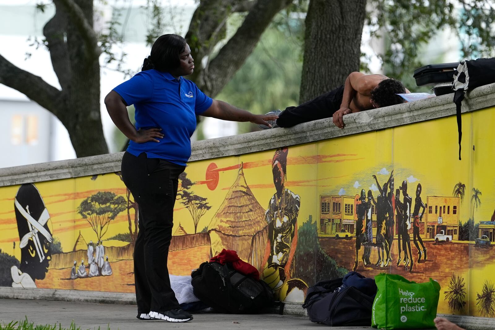 Erica Dorsett, program director of the TaskForce Fore Ending Homelessness, left, speaks with a homeless man who goes by the name of CJ on the first day of a statute that took effect, making it illegal in Florida to sleep on sidewalks, in parks, on beaches or in other public spaces — one of the country's strictest anti-homelessness laws, Tuesday, Oct. 1, 2024, in Fort Lauderdale, Fla. (AP Photo/Lynne Sladky)