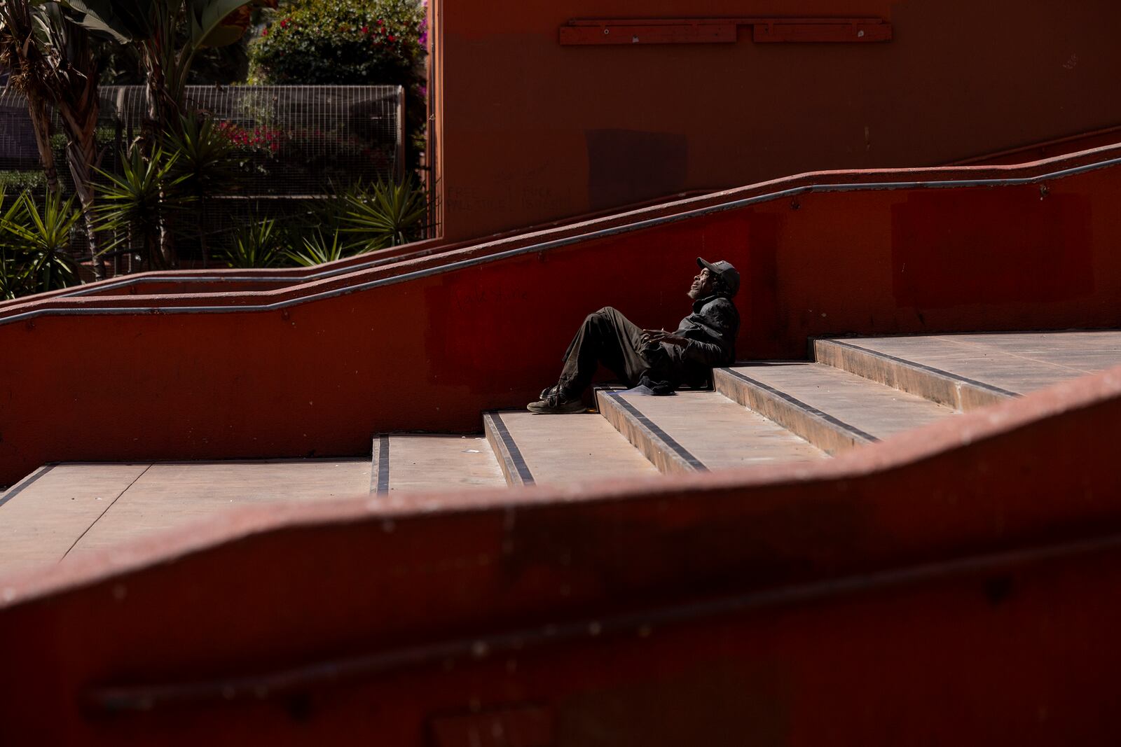 A person experiencing homelessness lays on a set of stairs in Pershing Square after a march to demand better wages and lower rent prices in Los Angeles, Saturday, Sept. 28, 2024. (AP Photo/Etienne Laurent)