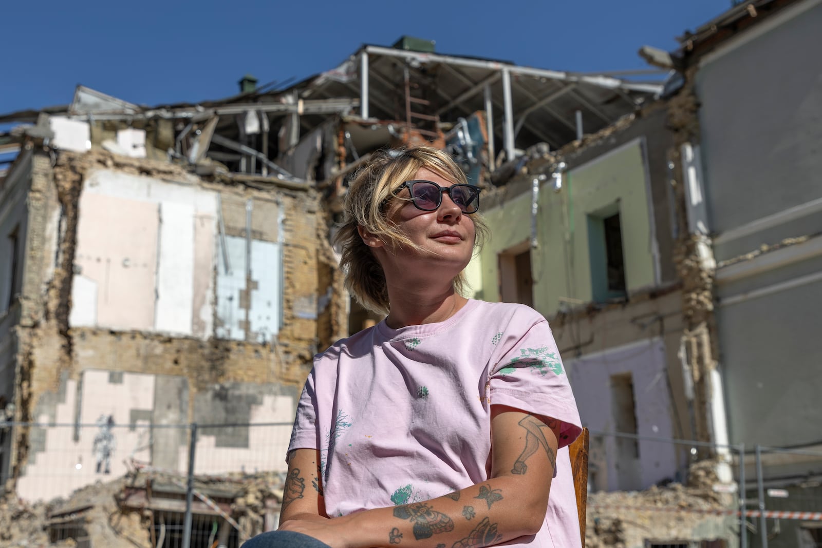 Olha Bulkina, 35, co-founder of the "Bureau of Smiles and Support" sits in front of Okhmatdyt children's hospital in Kyiv, Ukraine Saturday Sept. 14, 2024 which was destroyed after a Russian missile strike on July 8. (AP Photo/Anton Shtuka)