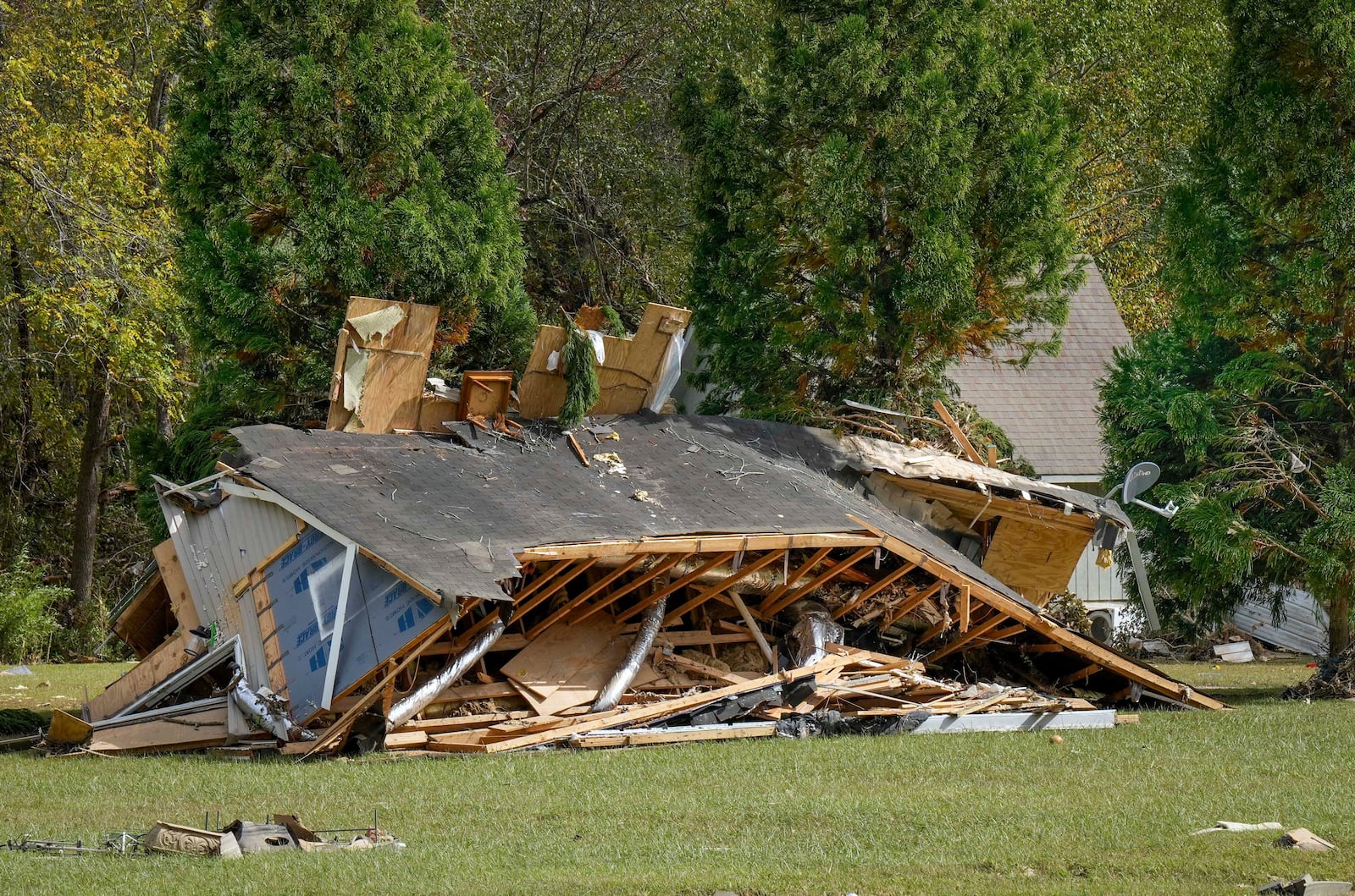 One of the homes belonging to the White family rests on its side in the aftermath of Hurricane Helene, Tuesday, Oct. 1, 2024 in Morganton, N.C. The adjacent Catawba River flooded due to torrential rains destroying seven of the family's nine homes on the property. (AP Photo/Kathy Kmonicek)