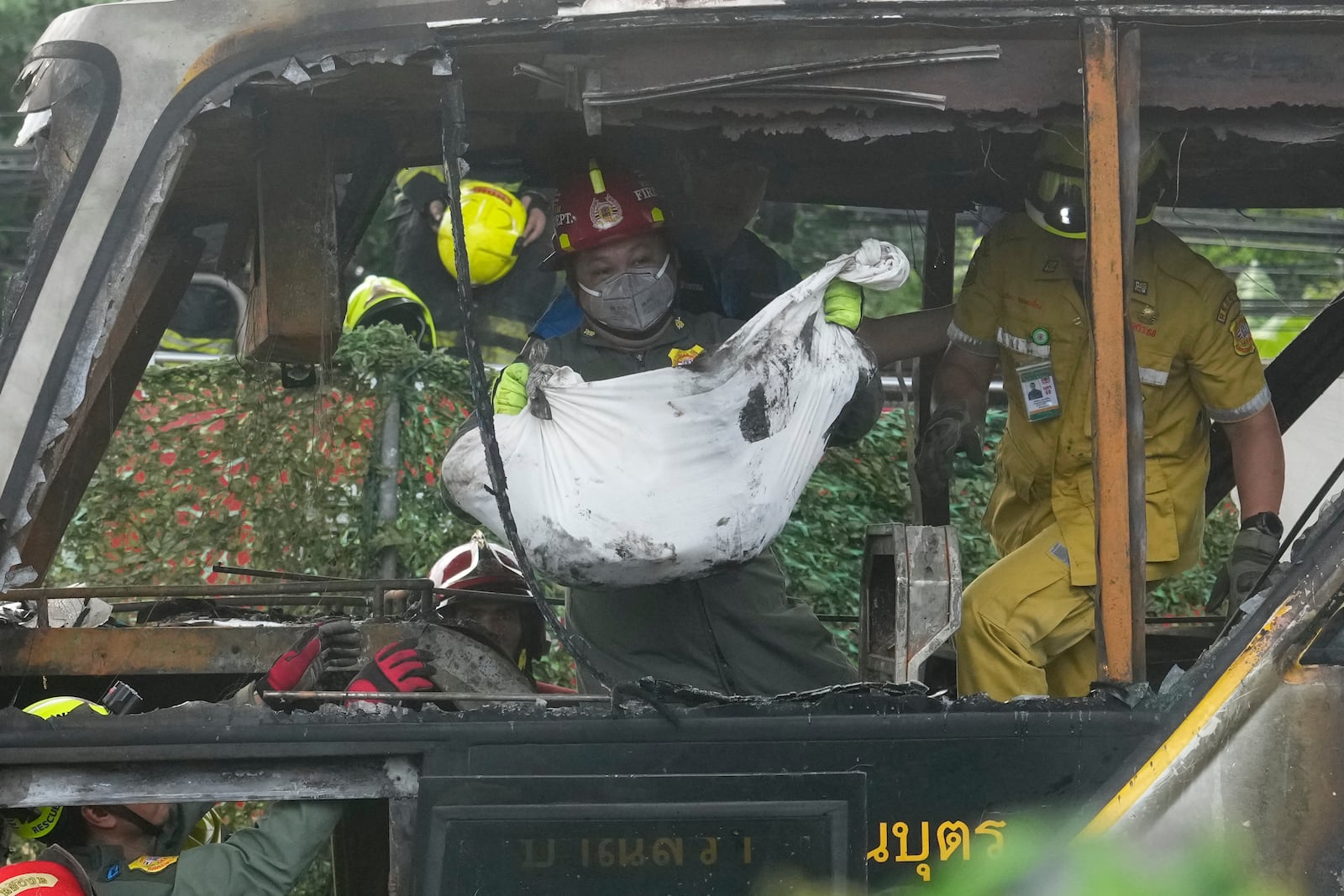 Rescuers carry the body of a victim of a bus that caught fire, carrying young students with their teachers, in suburban Bangkok, Tuesday, Oct. 1, 2024. (AP Photo/Sakchai Lalit)