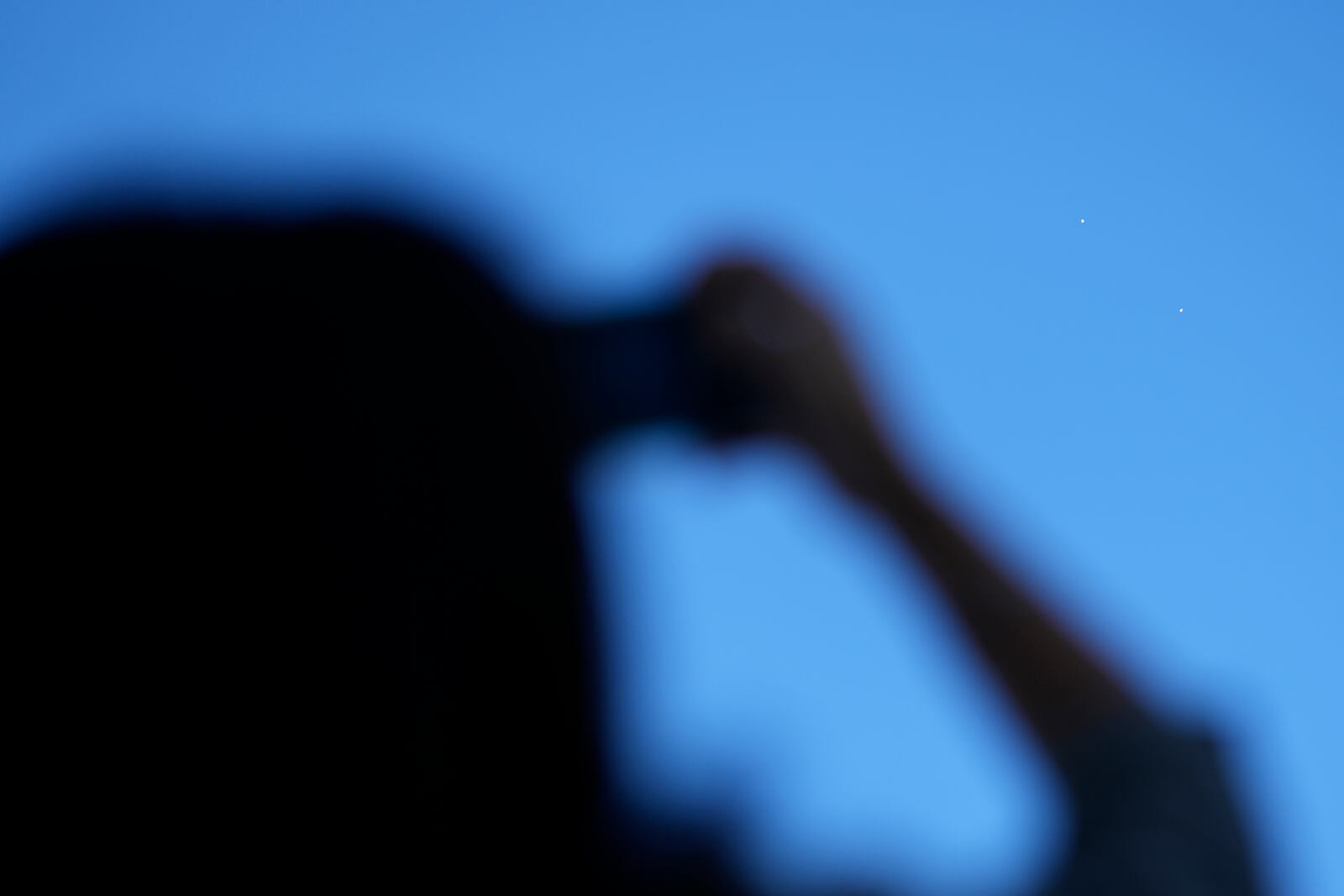 A visitor holds her smartphone from the Unification Observation Post in Paju, South Korea, as North Korean balloons, top right, fly, Friday, Oct. 4, 2024. (AP Photo/Lee Jin-man)